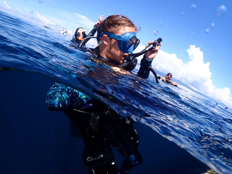 Dive professional Owen holding low pressure inflator hose at the surface preparing to descend with divers